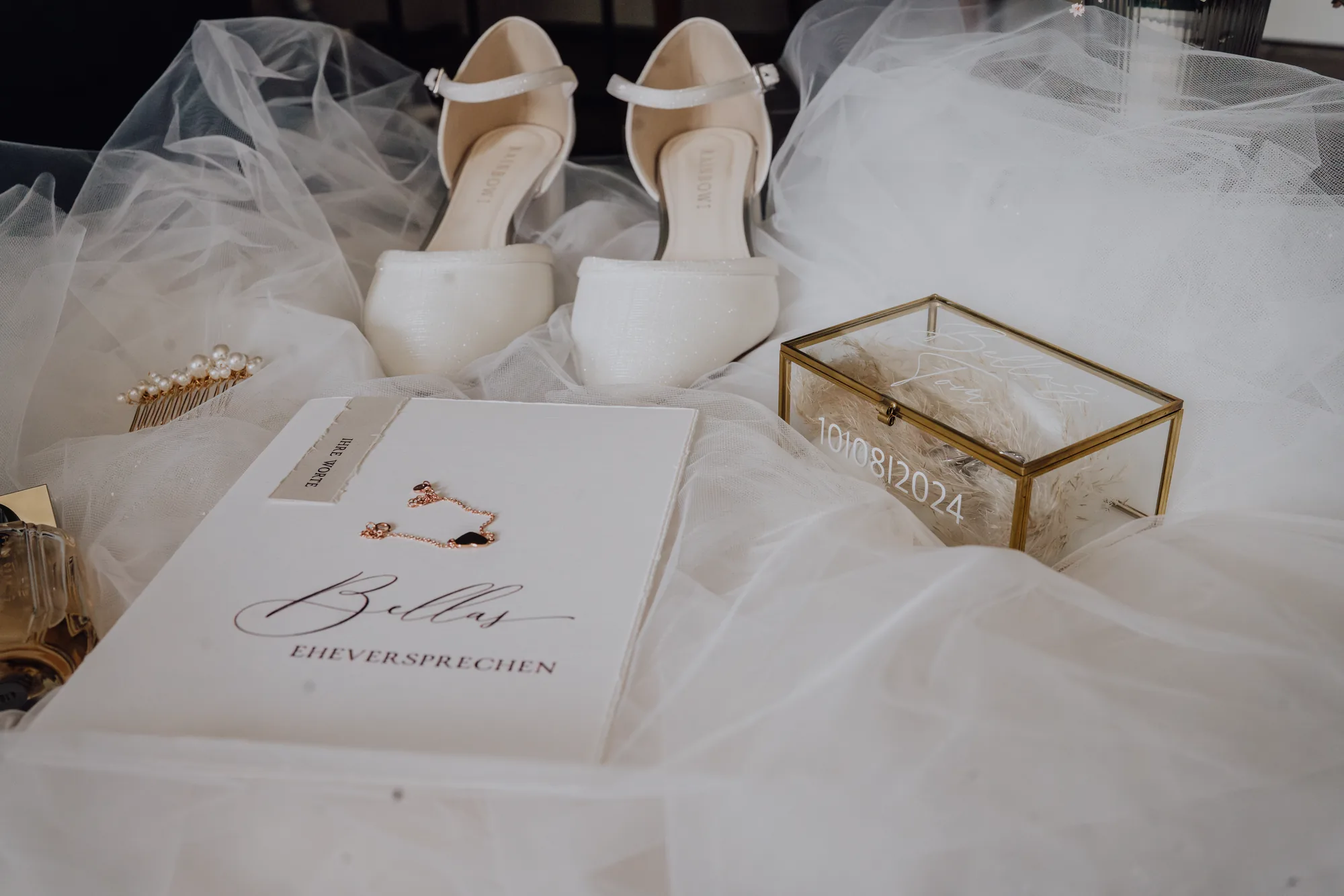 Bellas Brautschuhe, Haarkamm und Ohrringe auf dem Schleier, daneben ihr Eheversprechen und die Ringbox mit dem Hochzeitsdatum – Hochzeit Bella & Tom, Gut Immenhof, Malente
