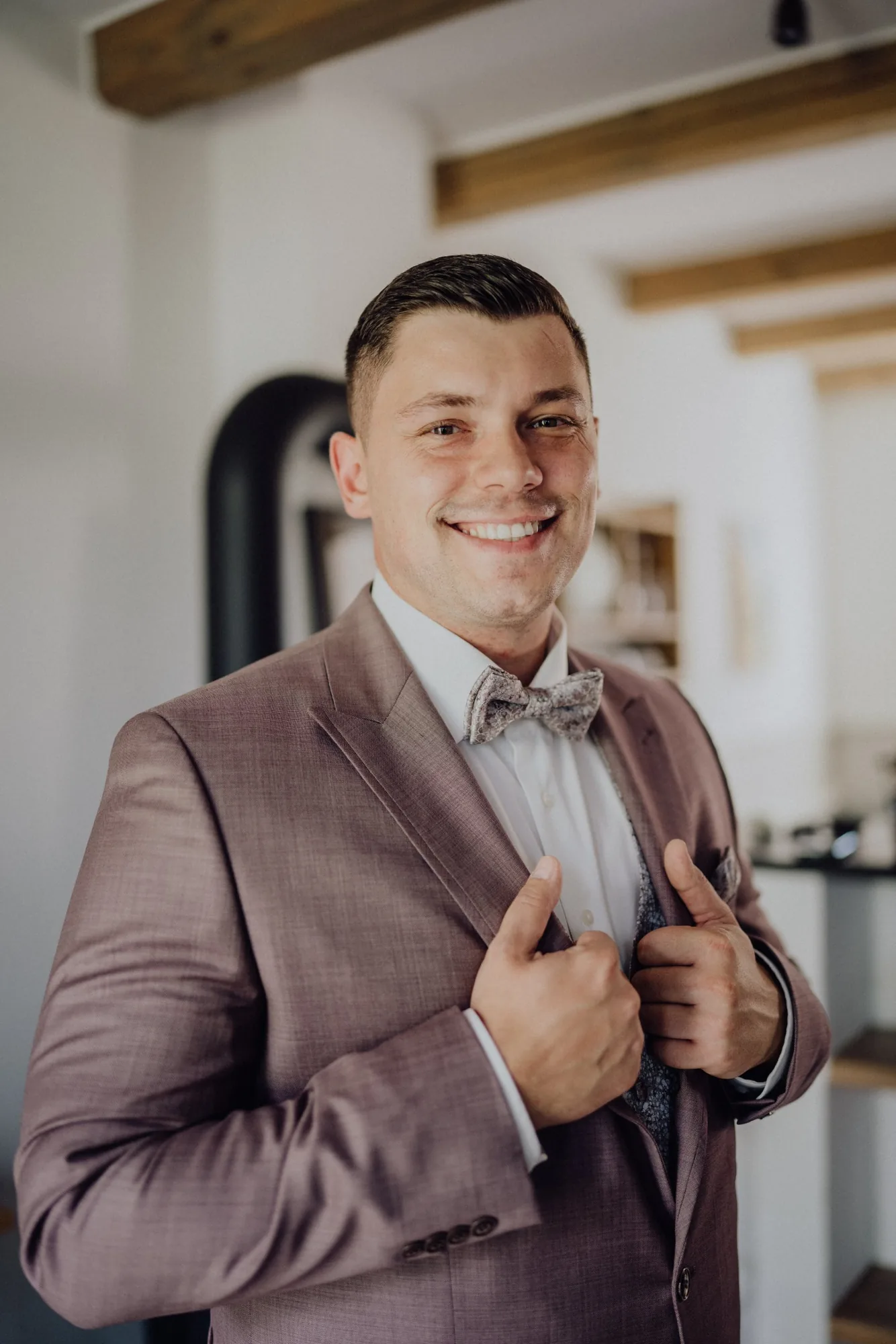 Tom im altrosa Anzug mit Fliege rückt sein Sakko zurecht – Hochzeit Bella & Tom, Gut Immenhof, Malente