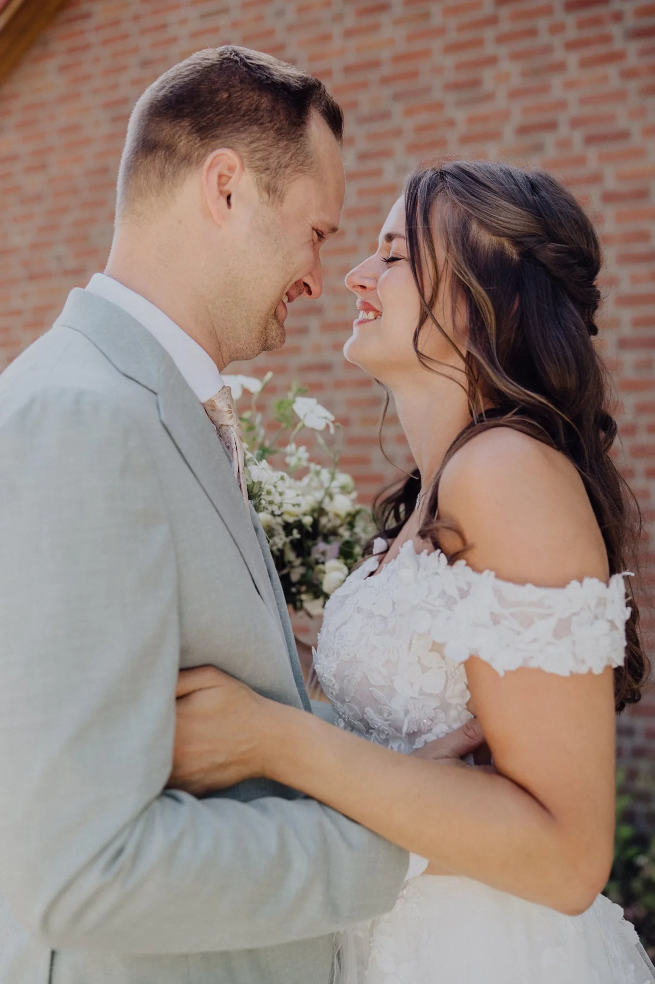 Franzi und Tim lachen sich Stirn an Stirn vor der Backsteinwand an – Hochzeit Franzi & Tim, De Ole Schüün, Hüttblek