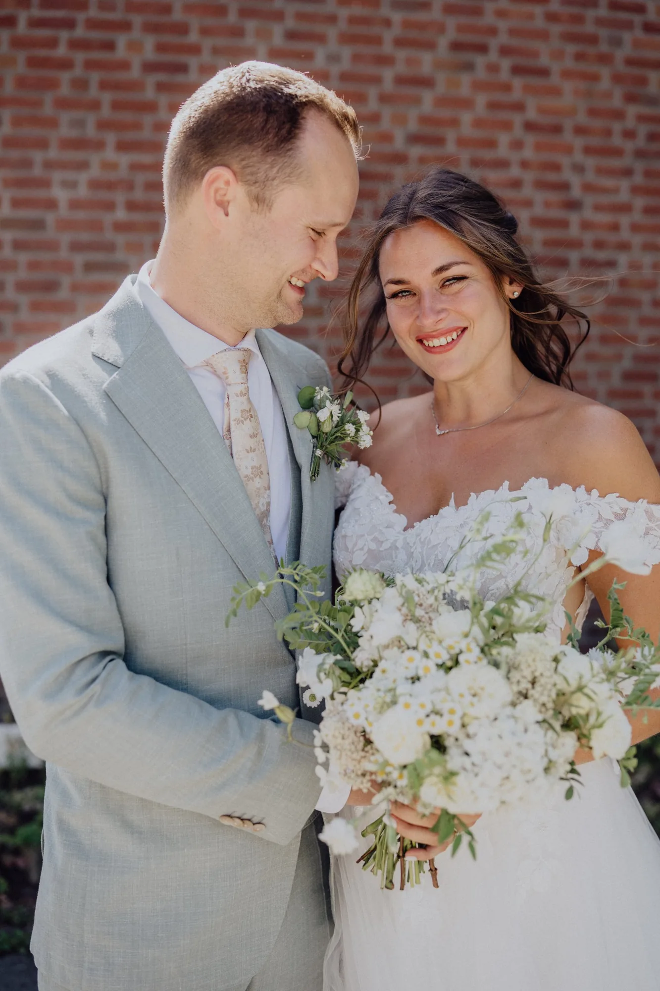Tim lächelt Franzi an, sie hält ihren weißen Brautstrauß – Hochzeit Franzi & Tim, De Ole Schüün, Hüttblek