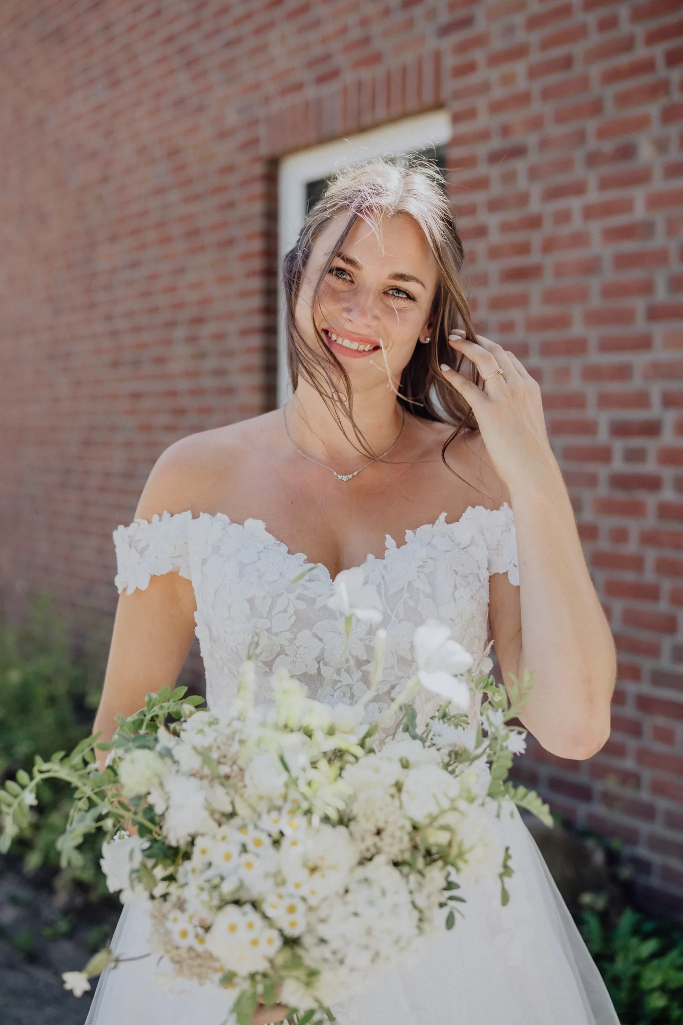 Franzi mit ihrem weißen Brautstrauß vor der Backsteinwand – Hochzeit Franzi & Tim, De Ole Schüün, Hüttblek