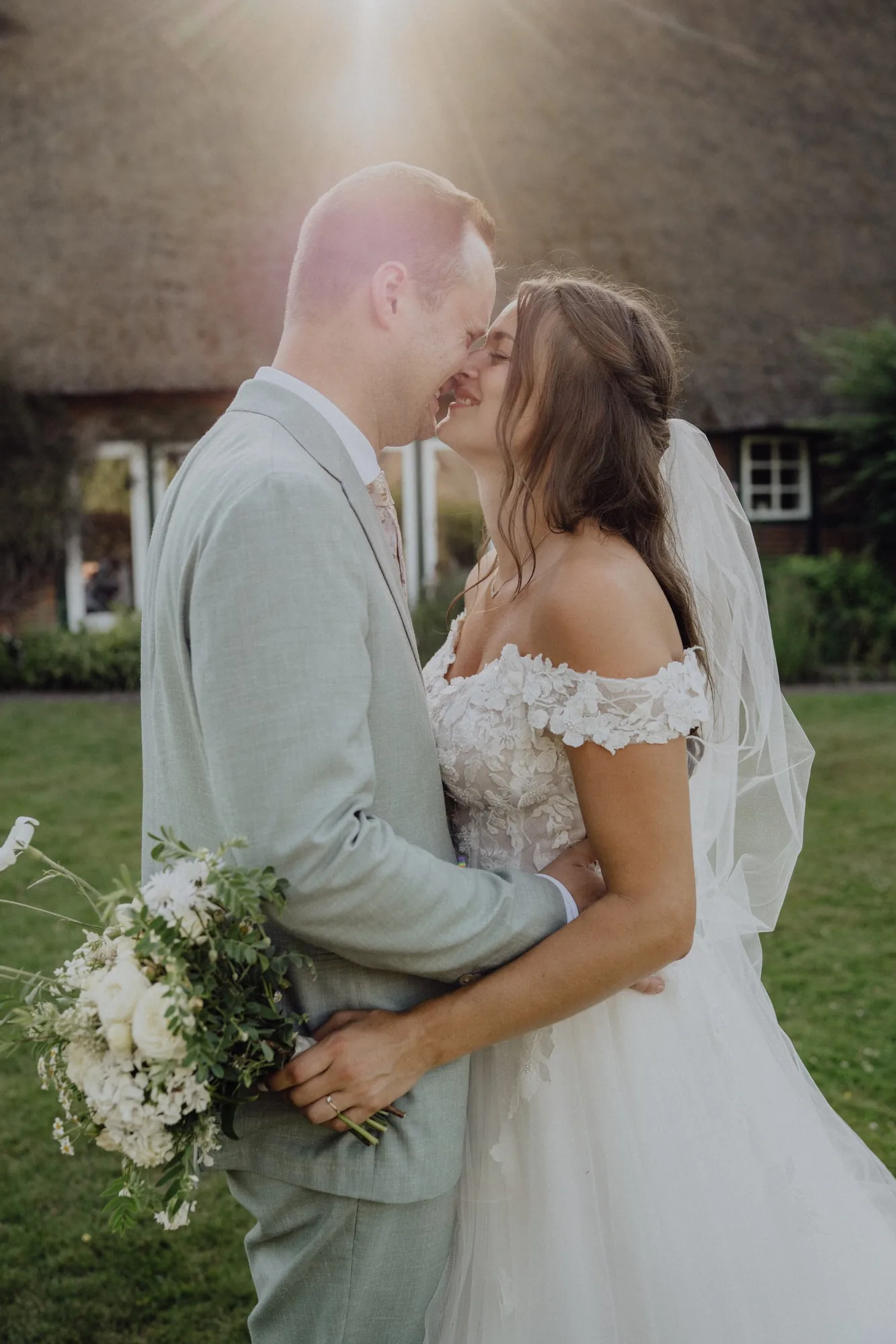Franzi und Tim küssen sich im Gegenlicht vor der Reetdachscheune – Hochzeit Franzi & Tim, De Ole Schüün, Hüttblek