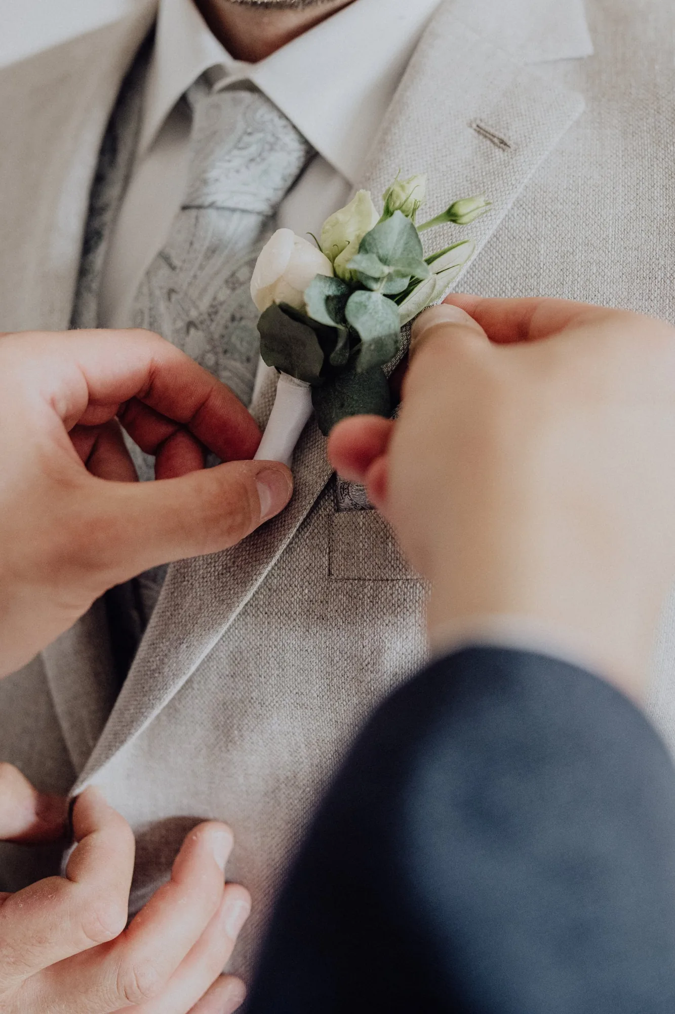Der Anstecker wird an Janniks Sakko befestigt – Hochzeit Maria & Jannik, Gut Pronstorf