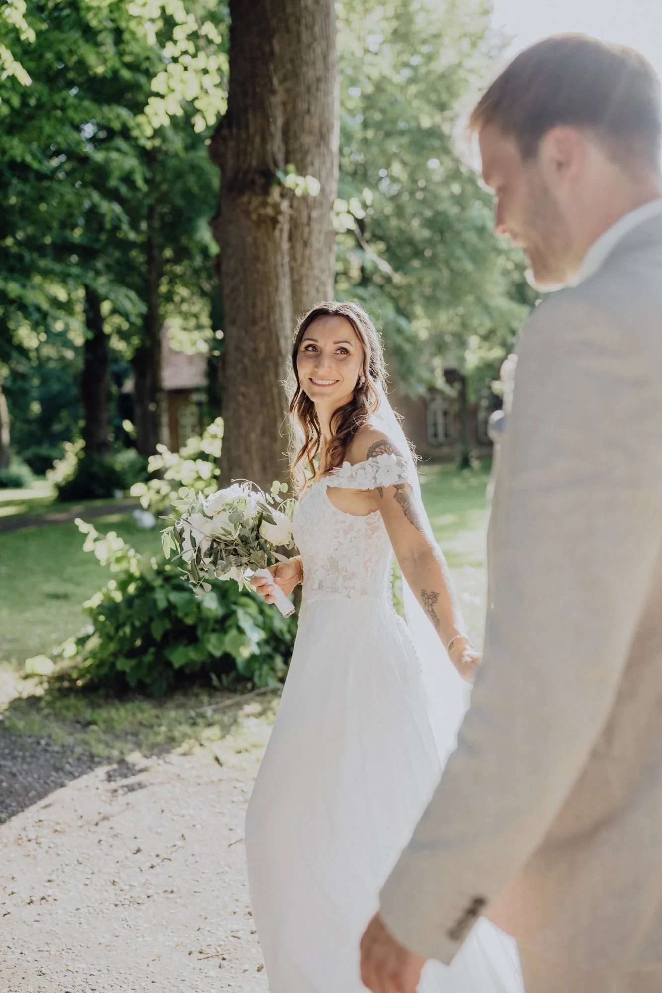 Maria schaut im Gehen über die Schulter zu Jannik zurück – Hochzeit Maria & Jannik, Gut Pronstorf