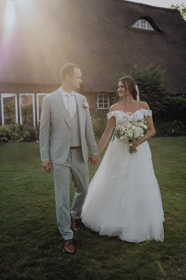 Franzi und Tim vor einem reetgedeckten Haus im Abendlicht