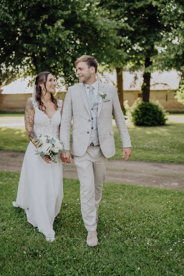 Maria und Jannik spazieren lachend über eine Wiese