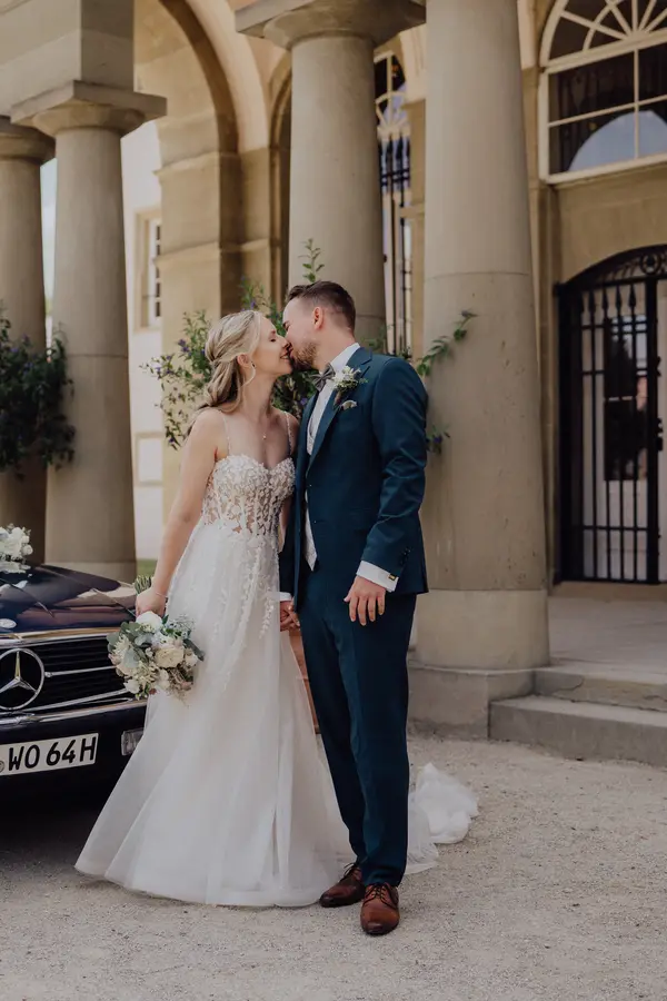 Natalie und Sven küssen sich vor einem Oldtimer-Cabrio