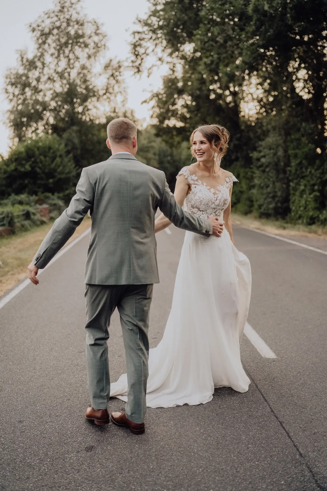 Sophie und Marc Hand in Hand auf einer Wiese im Gegenlicht